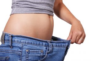 woman showing weight loss with loose jeans